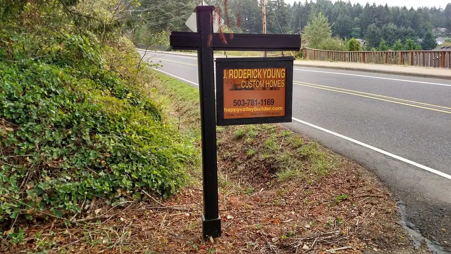 J Roderick Young Custom Homes job-site sign beside a road lined with trees