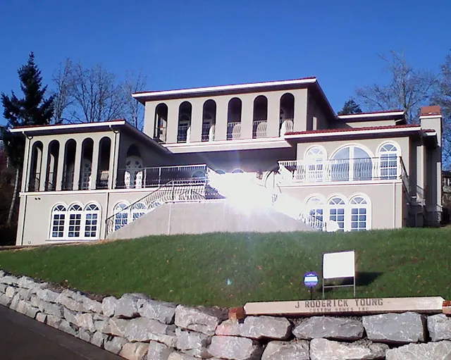 Hillside home with arched windows above a boulder wall
