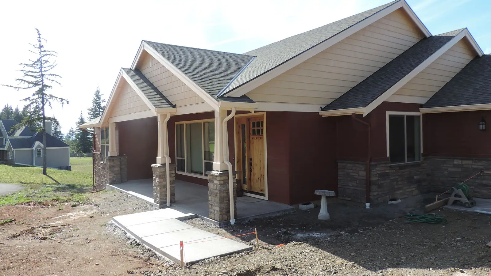 Craftsman home with red siding and stone-based columns