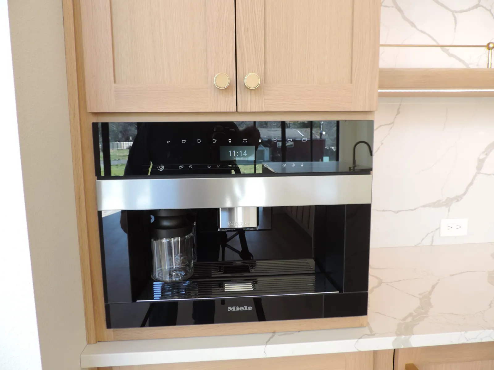 Built-in coffee machine set into white oak cabinetry