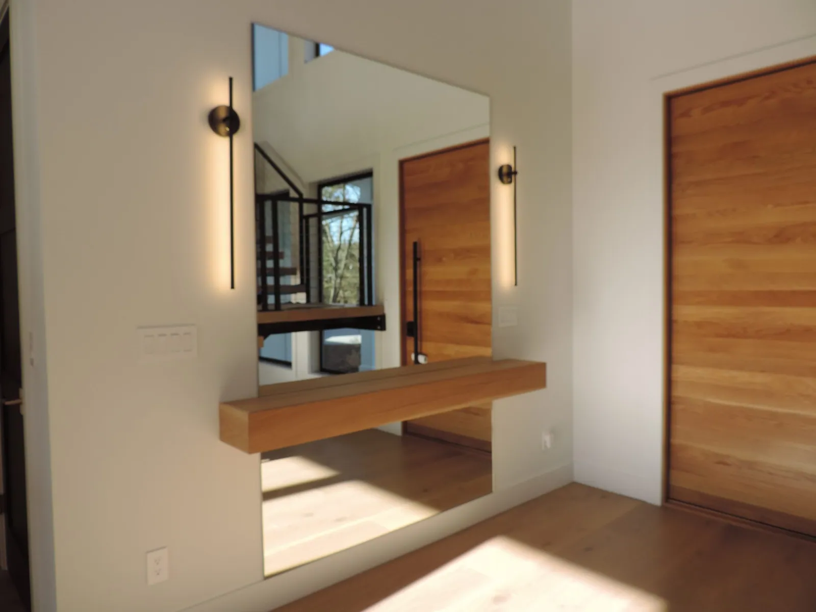 Finished entry with a white oak floating bench and wall sconce