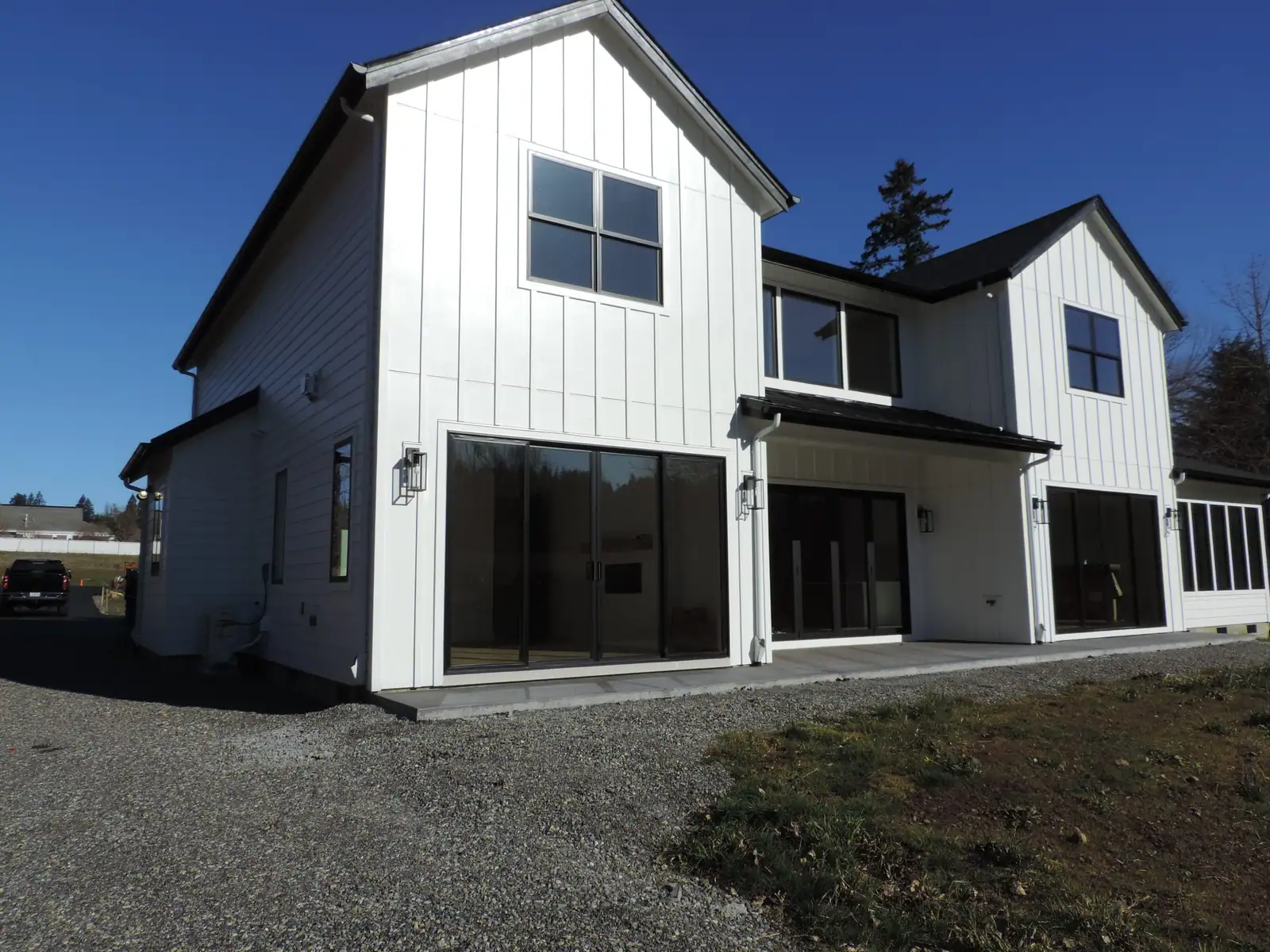Rear of a white custom farmhouse with large black sliding doors