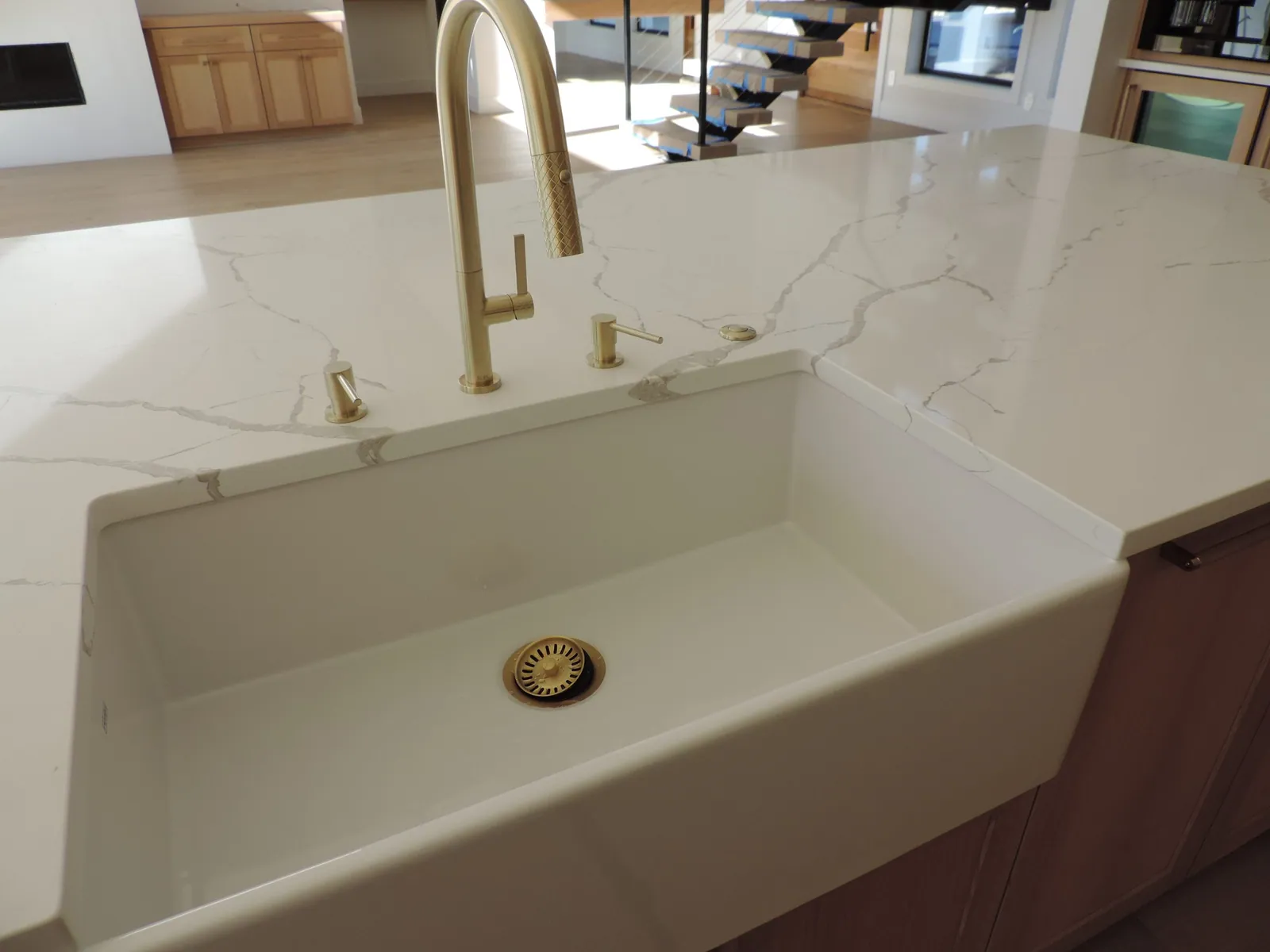 Farmhouse sink with a brushed brass faucet and quartz counter