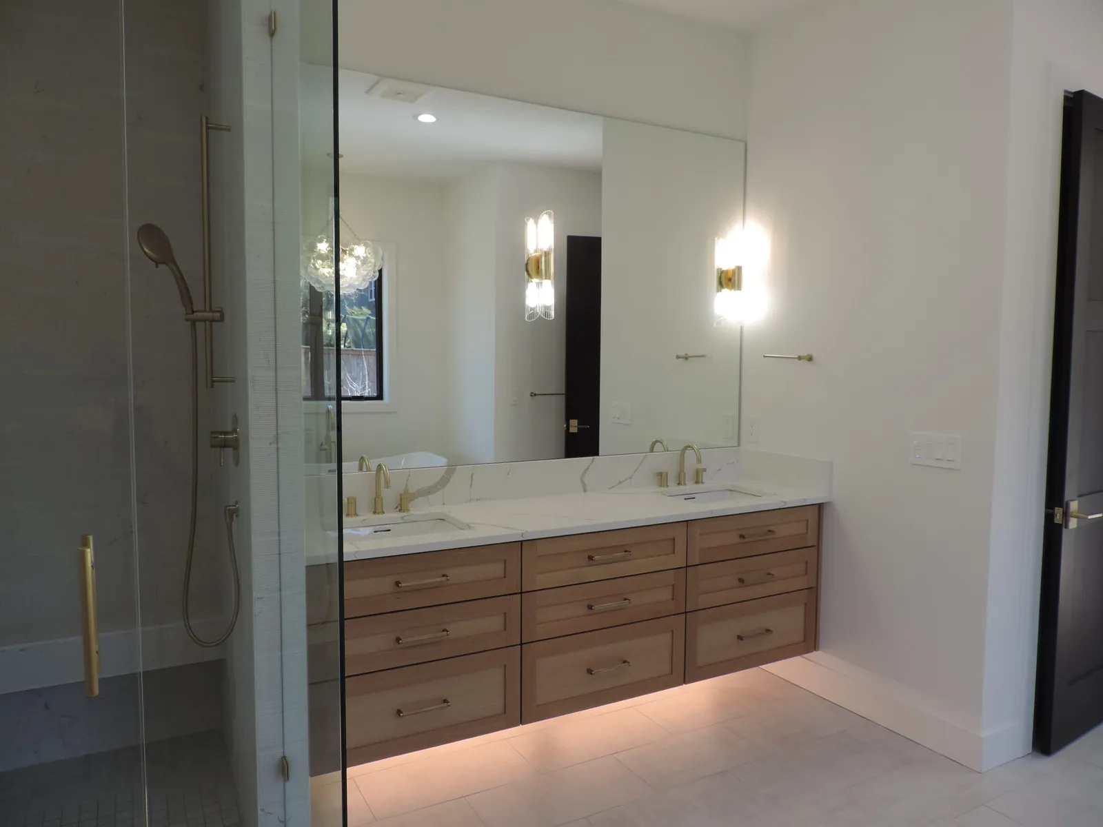 Floating white oak vanity with brass sconces