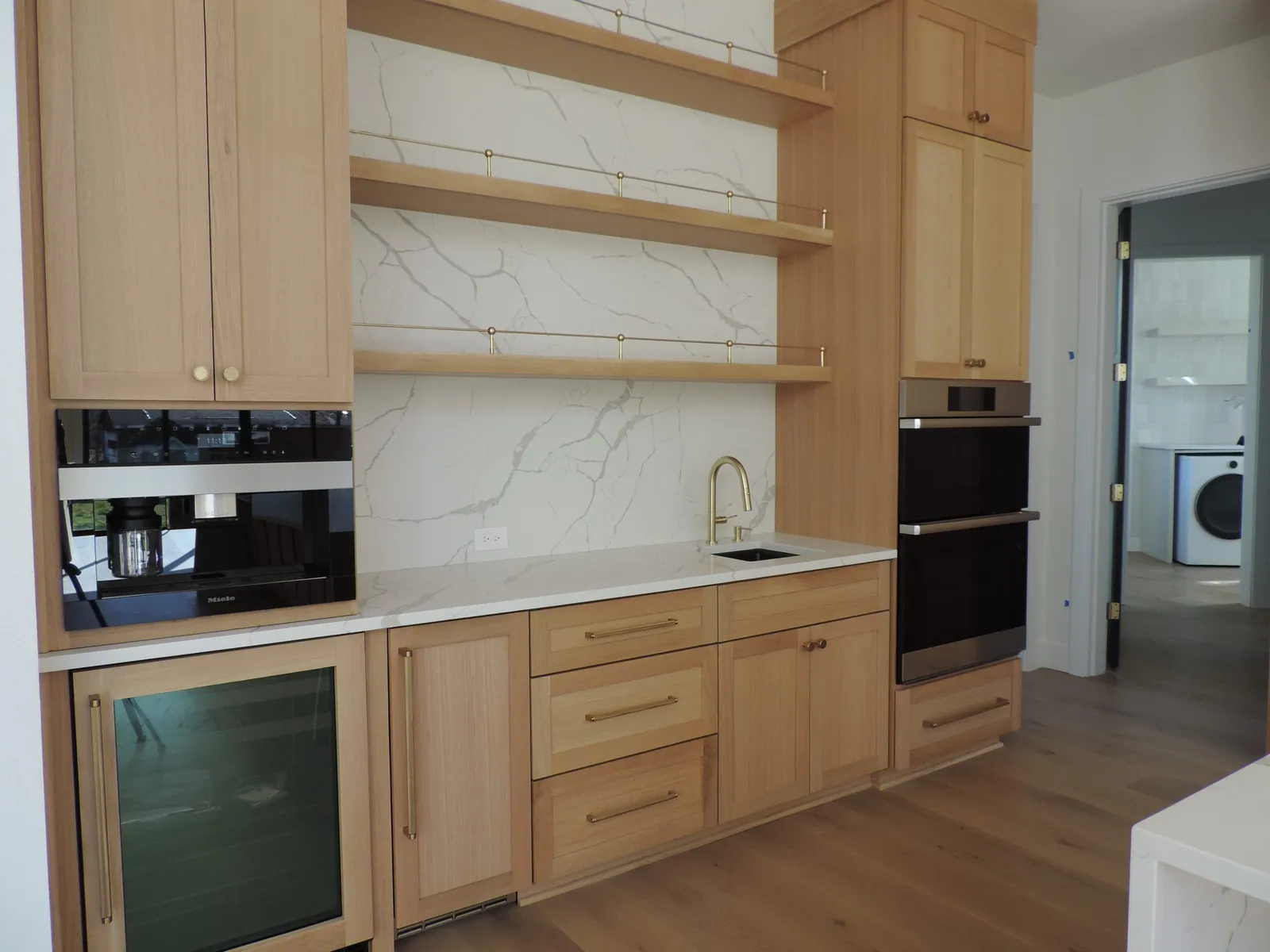 Kitchen nearing completion with built-in ovens and floating shelves