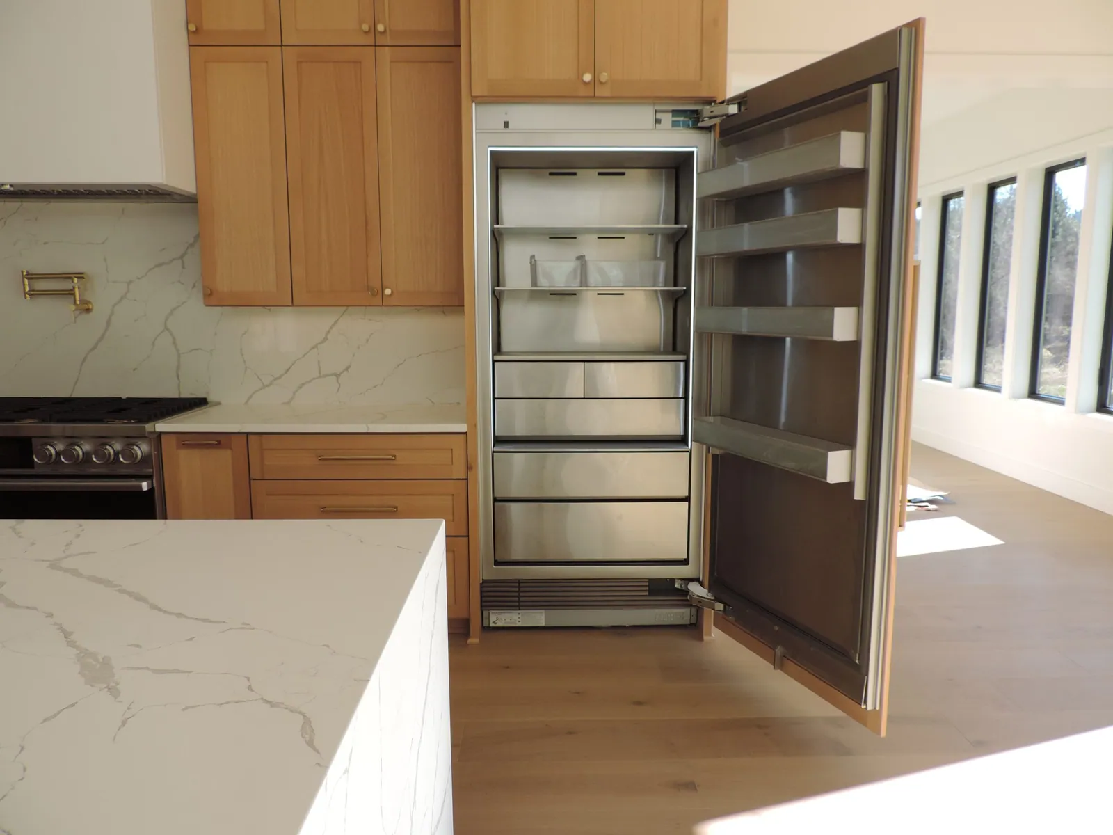 Panel-ready column refrigerator opened in white oak cabinetry