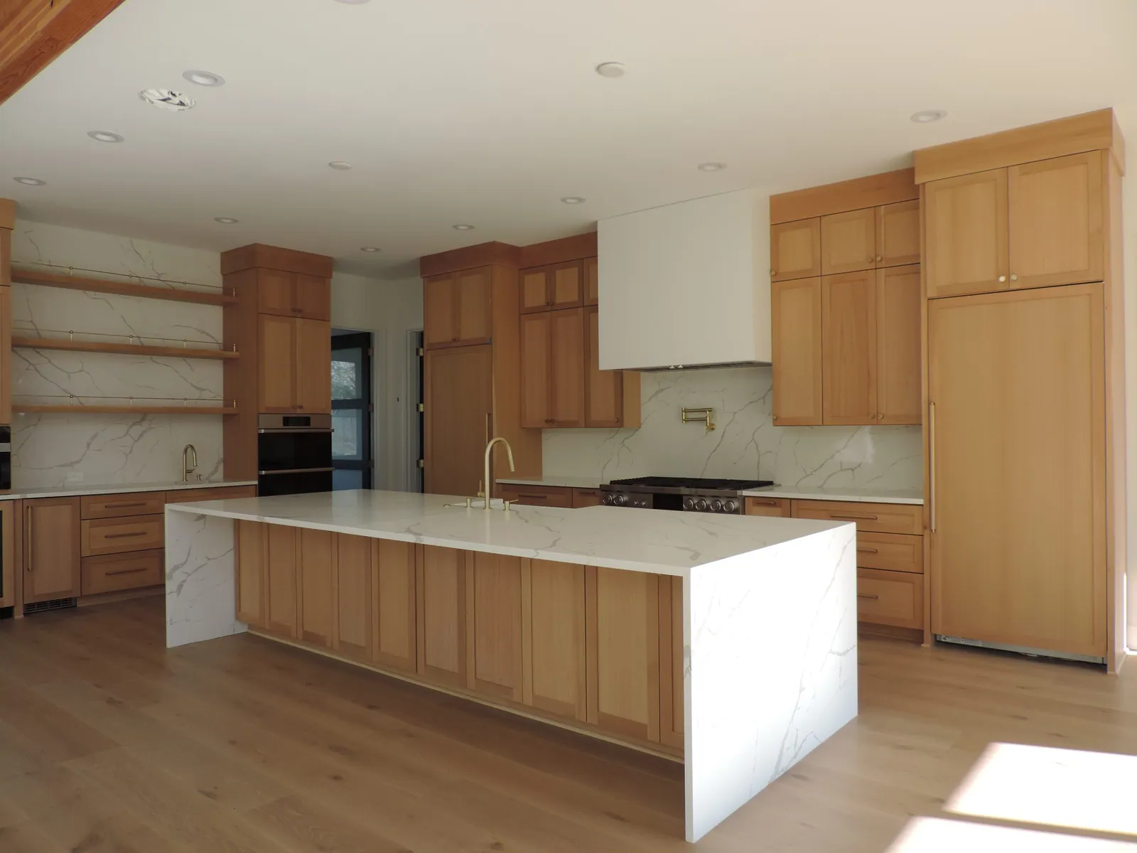 Waterfall quartz island in a white oak kitchen