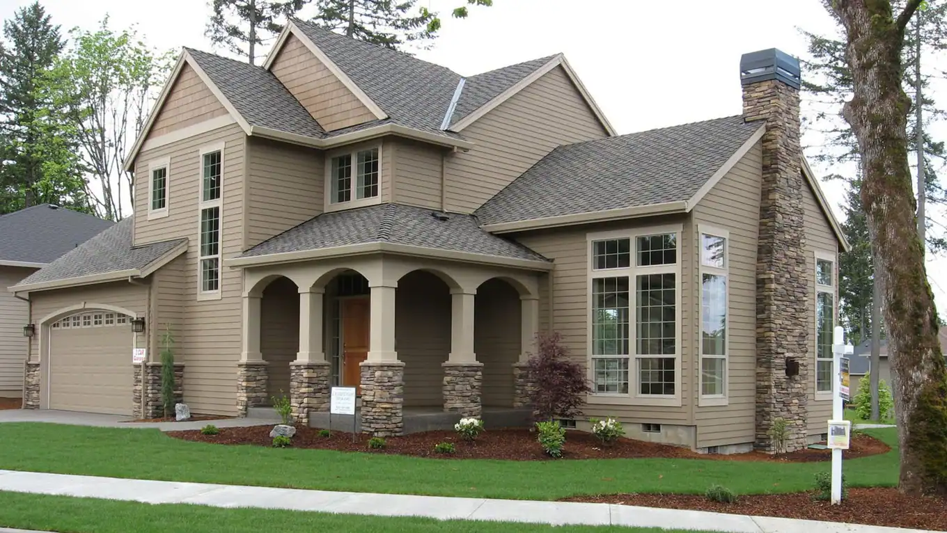 Two-story craftsman home with a tall stone chimney and landscaped yard