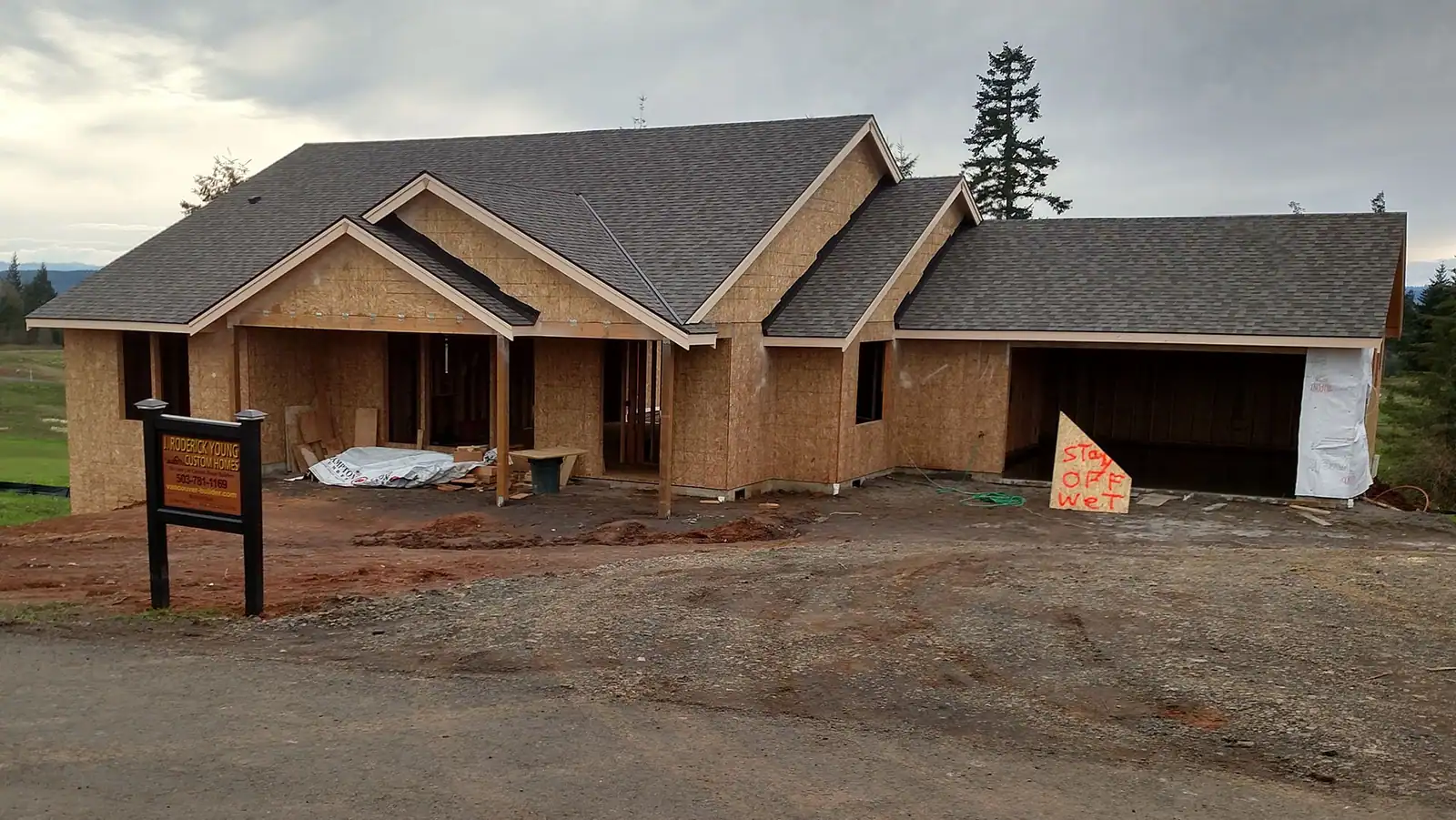 A home at framing and sheathing stage with a builder's sign out front